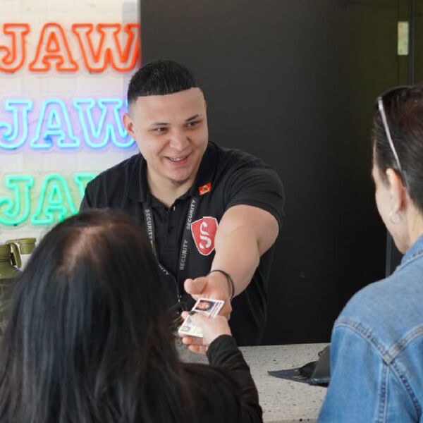 Semper Secure officer checking a visitor ID at a front counter