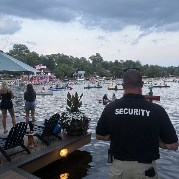 Security officer overlooking a lake filled with kayaks and canoes during a community event