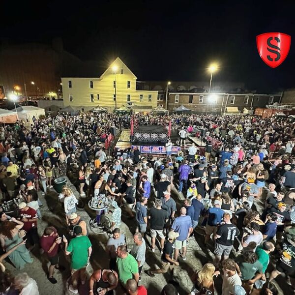 Large nighttime outdoor event crowd gathered around a wrestling ring